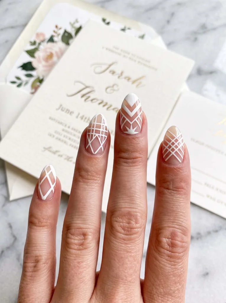 close-up of negative space French tip wedding nails beside a wedding invitation
