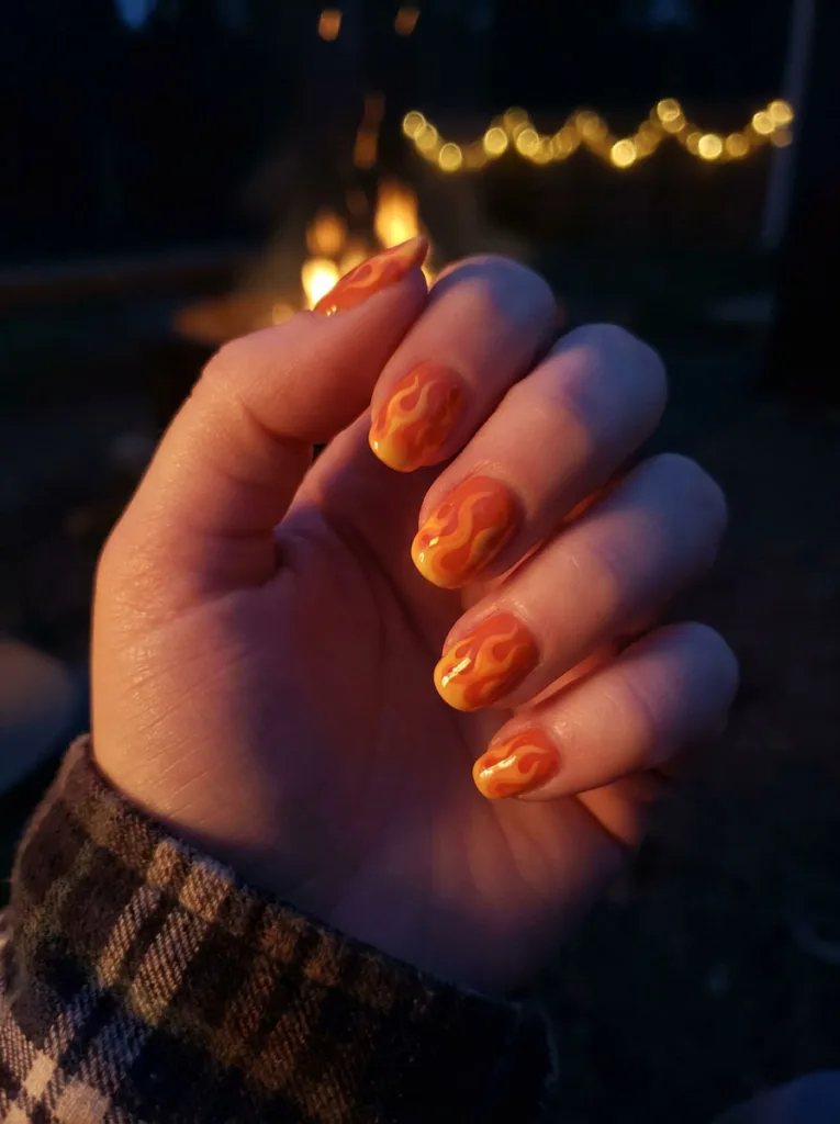 Neon flame nail design with orange and yellow fire accents