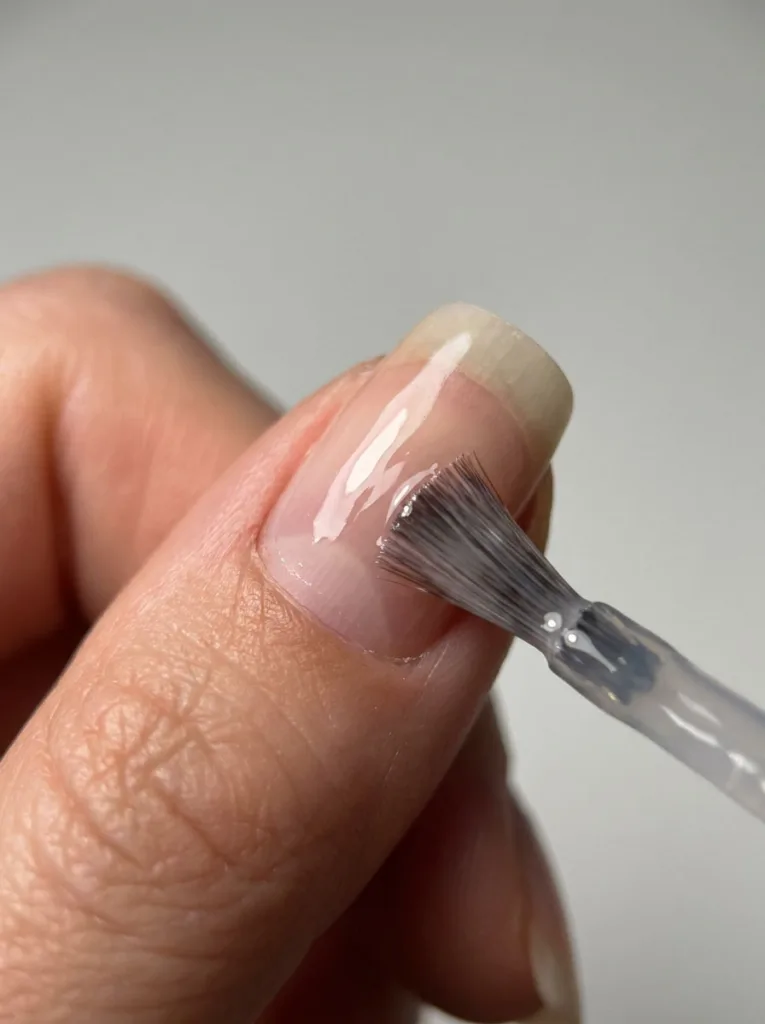 Applying a clear base coat to prevent common summer nail mistakes