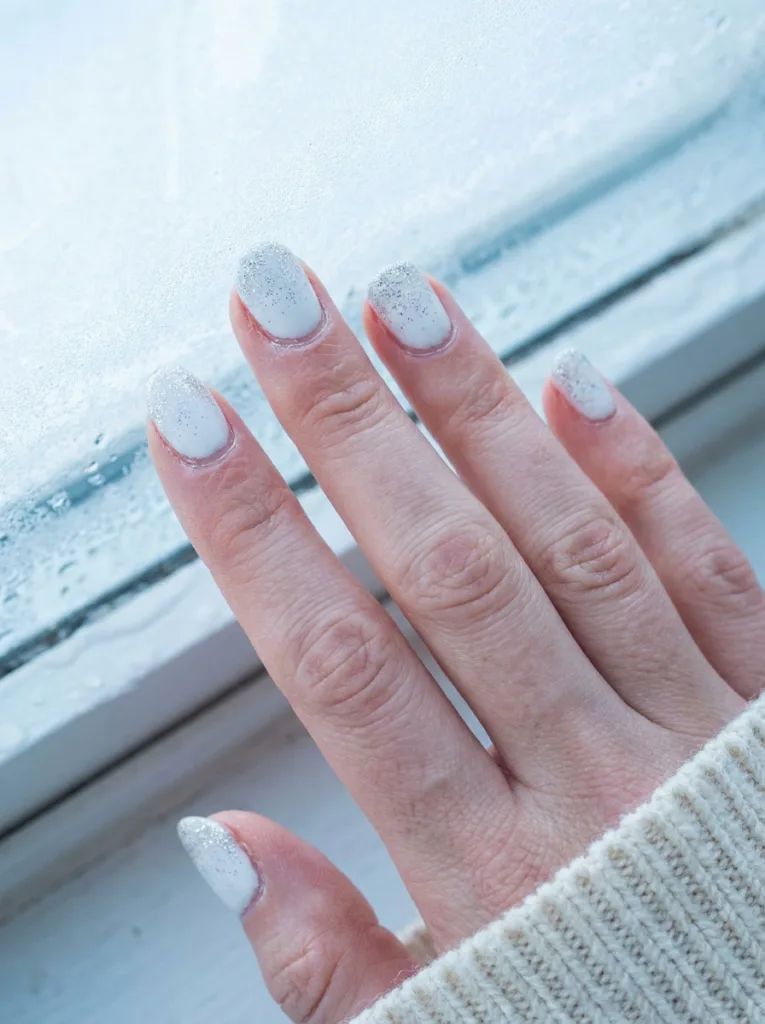 White nails with silver glitter dust tips, an icy holiday nail art look