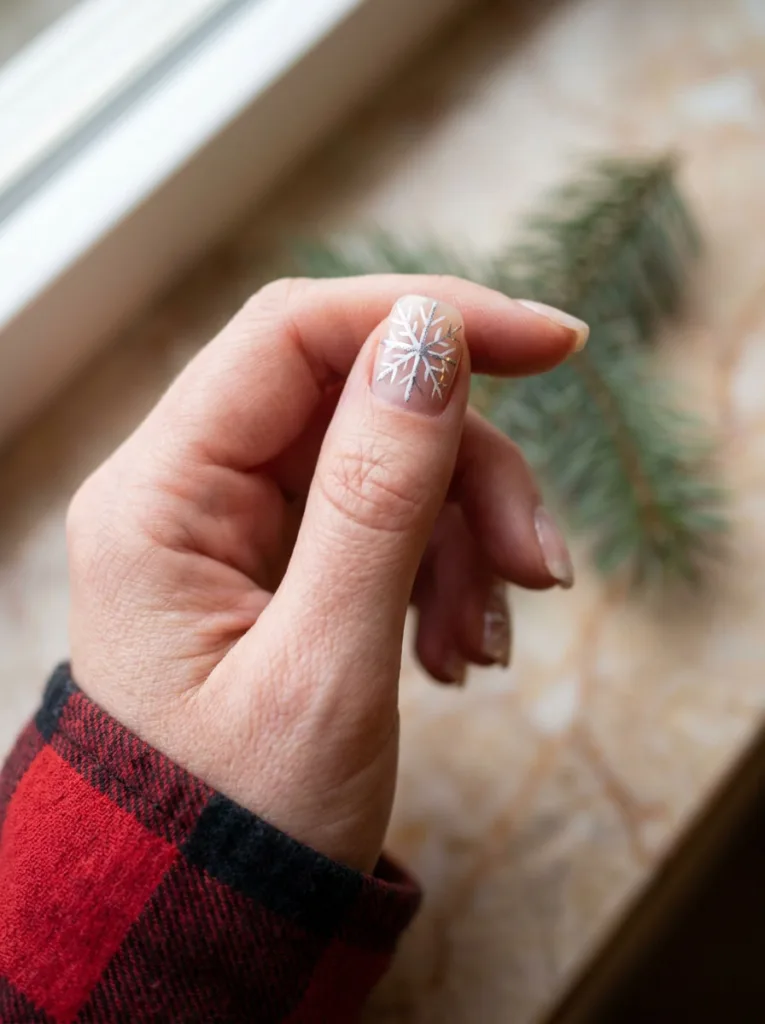 Hand painted snowflake nail art on a white Christmas manicure