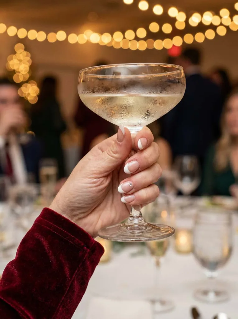 White French tip nails with a rhinestone accent at a holiday party