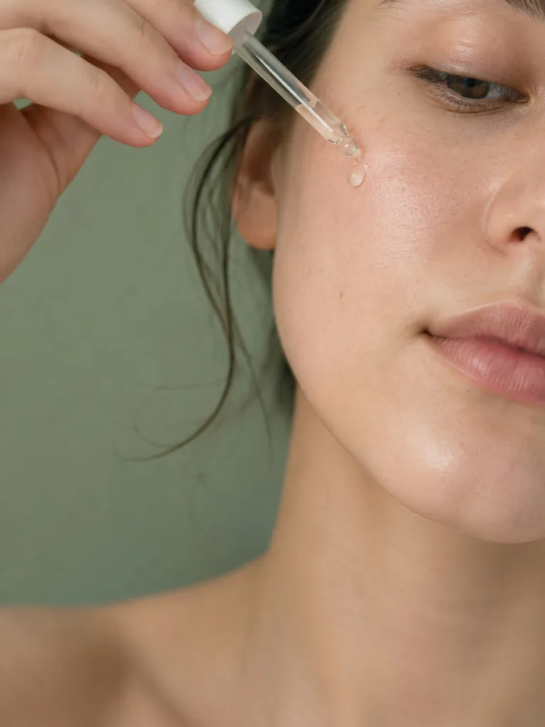 Close-up of essence being applied to the face with a glass dropper for hydration