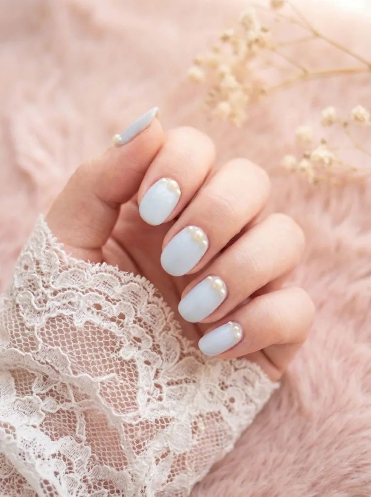 Baby blue winter nails with tiny pearl details near the cuticle