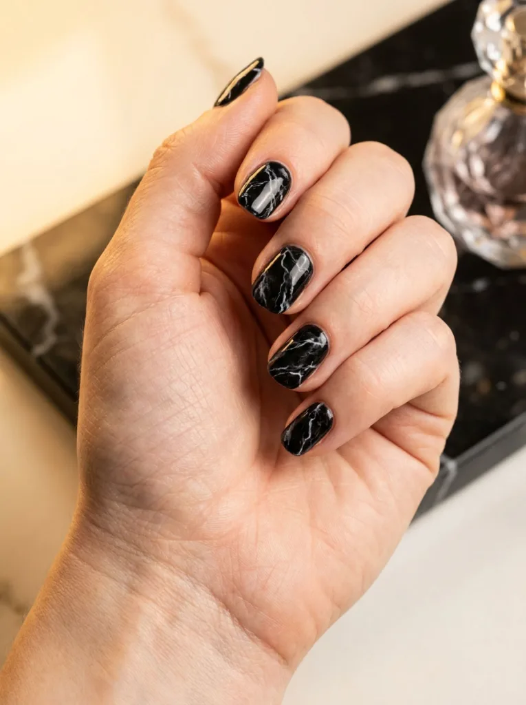 Close-up of a hand turned three-quarter angle showing a black and white marble-effect manicure