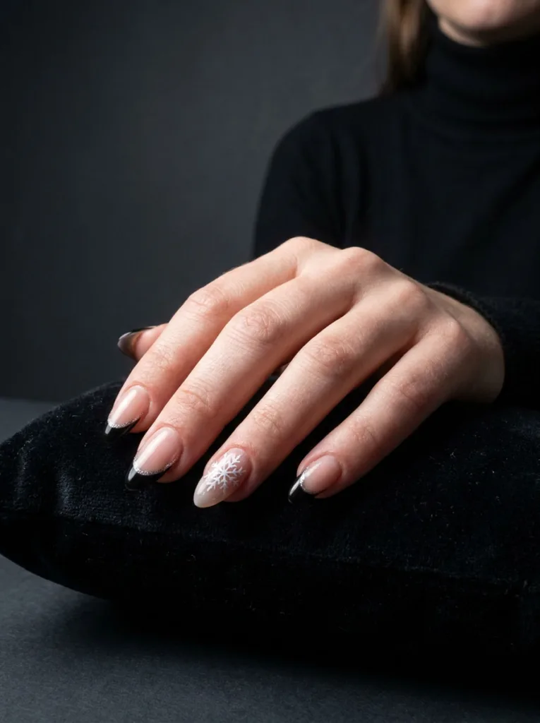 Hand with black and silver glitter French tip nails resting on a dark velvet cushion