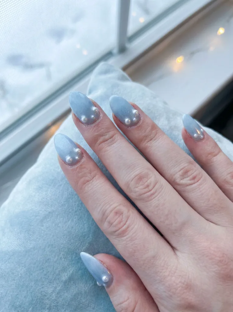 Cool blue new years nails with pearl embellishments near the cuticle