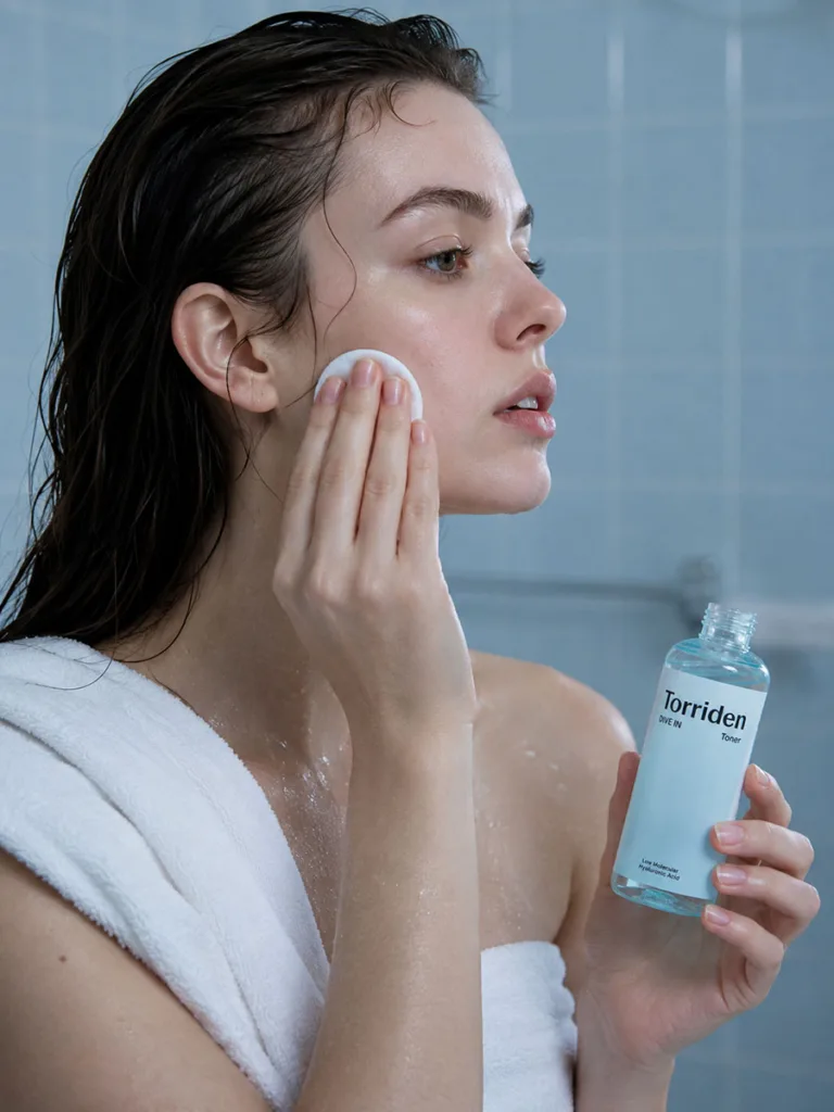 Woman patting Torriden hyaluronic acid toner onto damp skin after showering