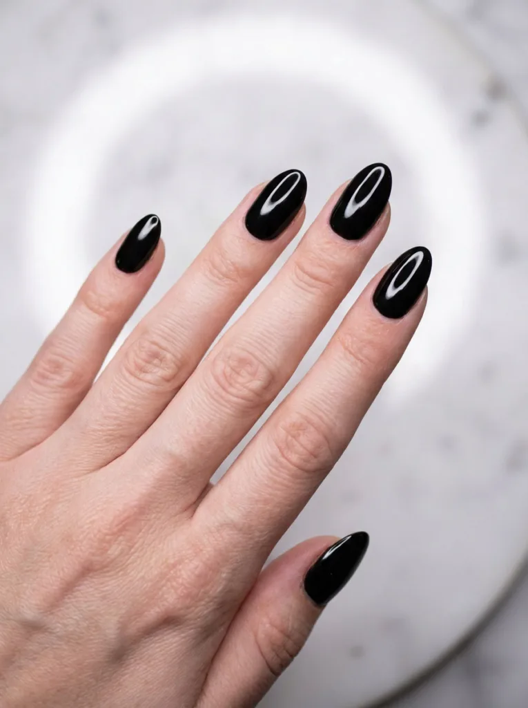 Close-up of a fair-skinned hand with a glossy black manicure, fingers fanned flat
