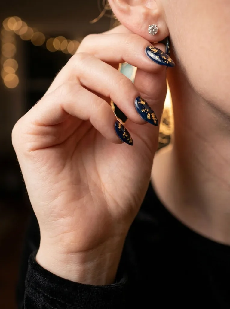 Midnight navy winter nails with gold foil flecks for evening wear