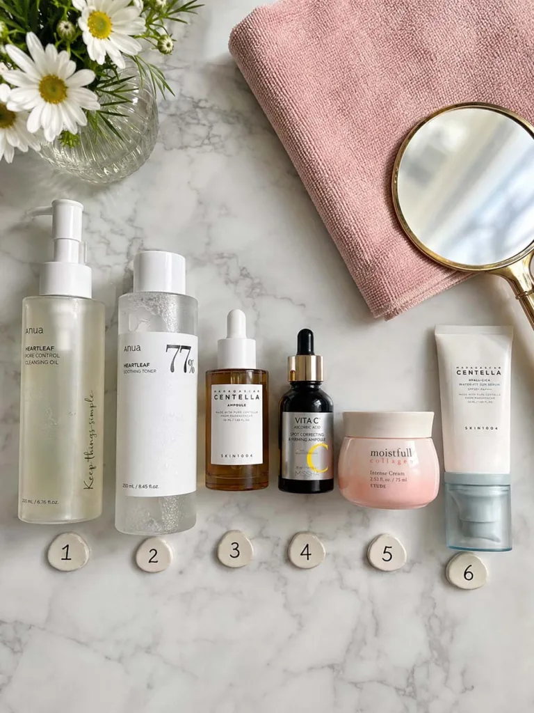 Flat lay of six Korean morning skincare products arranged in routine order on a marble surface