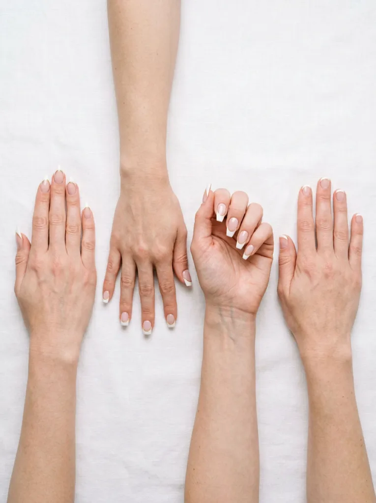 Four hands showing almond, square, coffin, and short round nail shapes with French tip Christmas nails