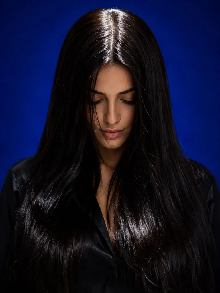 Glossy noir brown hair color against a vibrant sapphire blue studio backdrop
