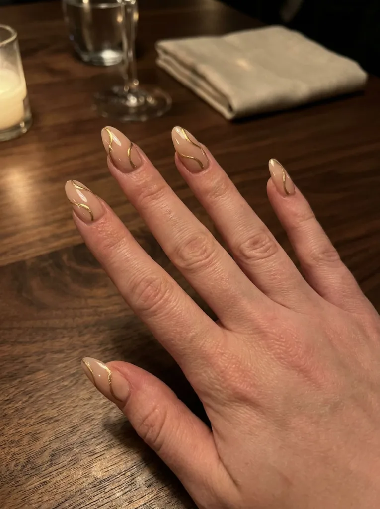Nude birthday nails with hand-painted gold swirl details