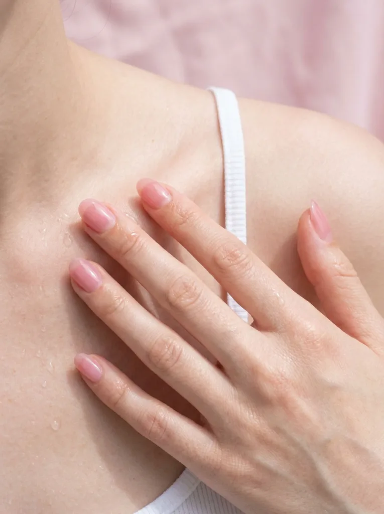 Fair-skinned hand near collarbone showing sheer pink jelly simple winter nails