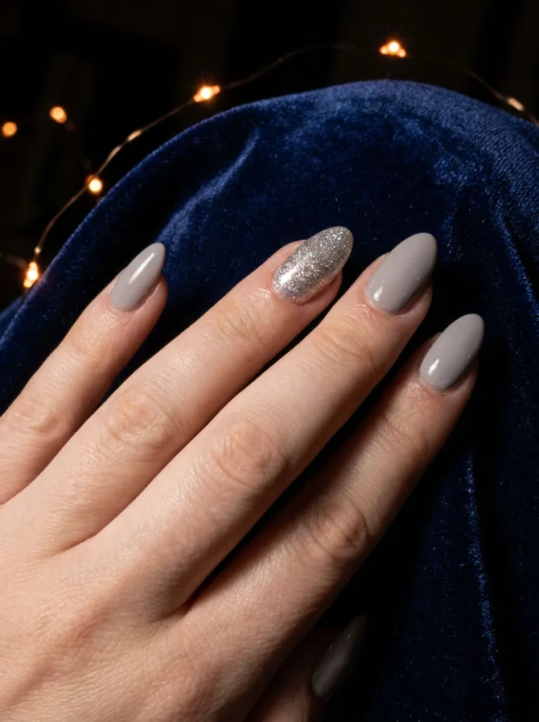 Fair-skinned hand fanned out showing a silver glitter accent nail among neutral simple winter nails