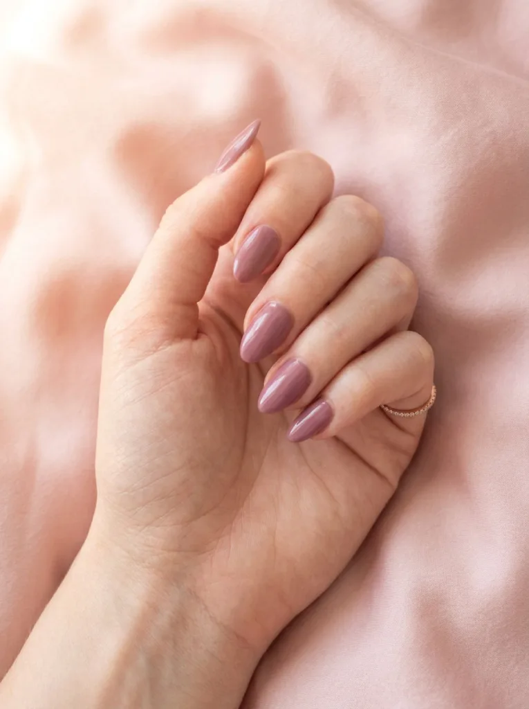 Fair-skinned hand resting on blush pink silk fabric showing soft mauve simple winter nails