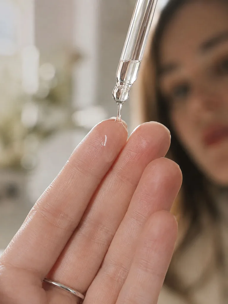 Macro shot of essence droplet on fingertips before application
