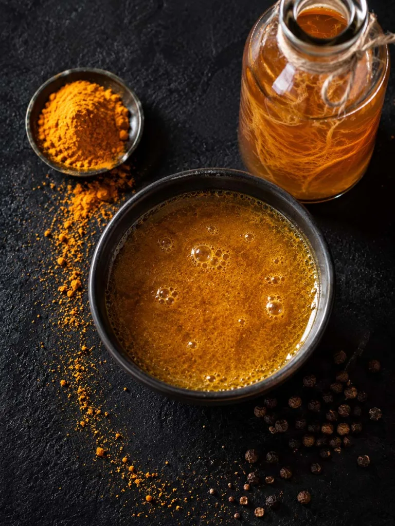 Turmeric powder and apple cider vinegar styled together for a homemade blackhead-clearing face mask