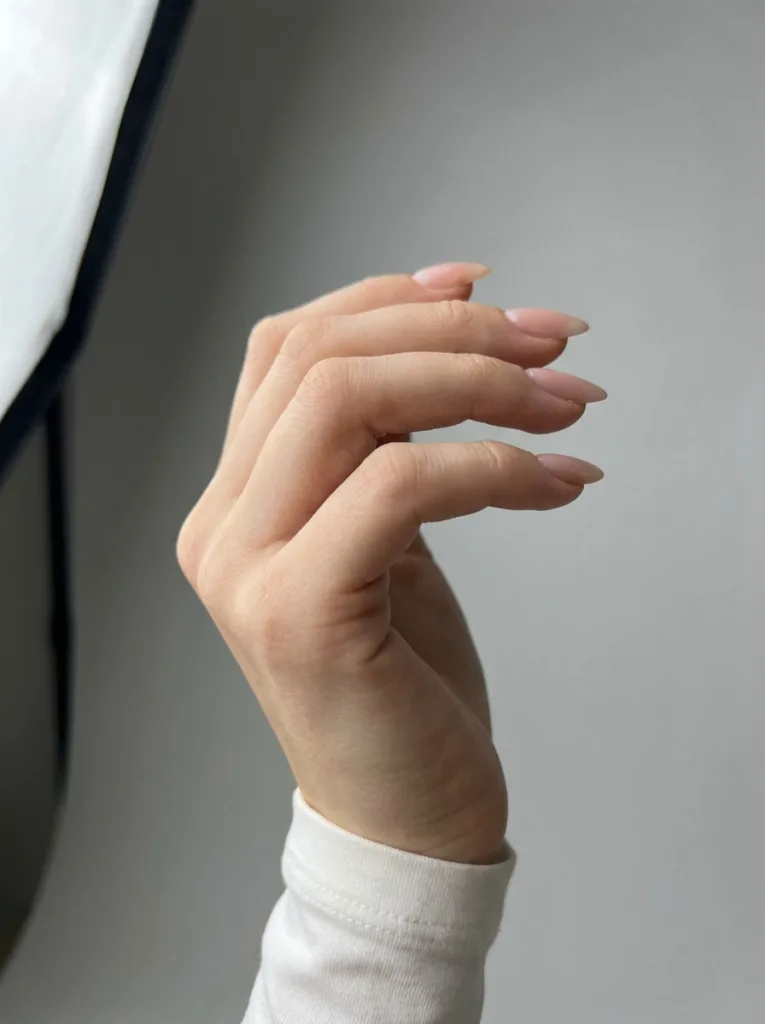 Side profile of a fair-skinned hand showing the tapered almond nail shape