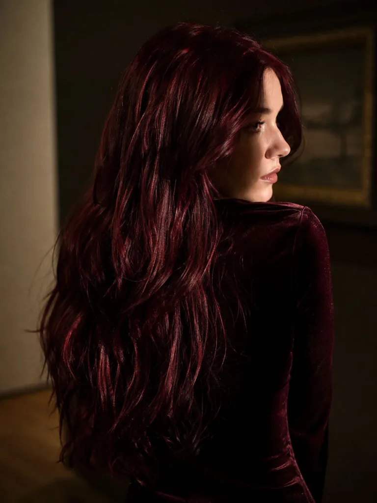 Woman showing deep burgundy fall hair color from behind in moody lighting
