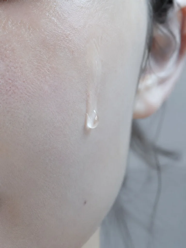 Macro close-up of a fermented Korean essence droplet absorbing into dehydrated skin