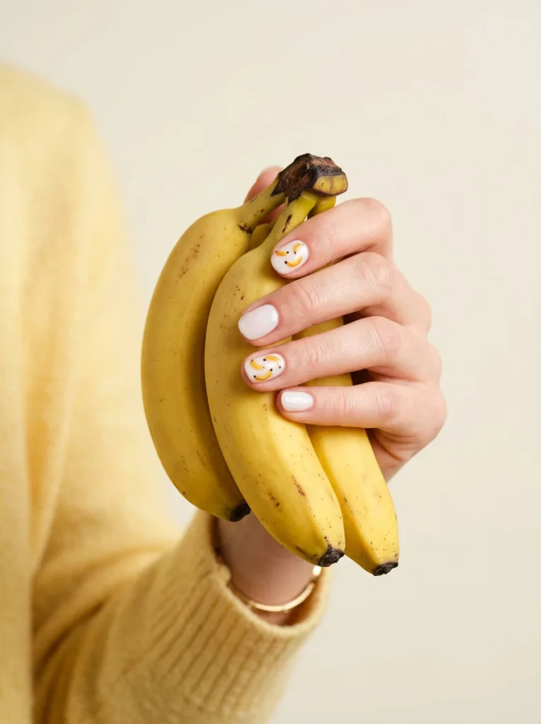 Banana bunch fruit nail design on a hand holding a small bunch of bananas