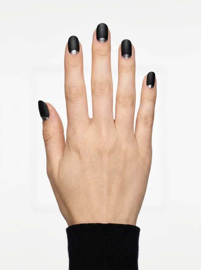 Fair-skinned hand with graphic silver chrome half-moon nails against a minimalist white studio backdrop