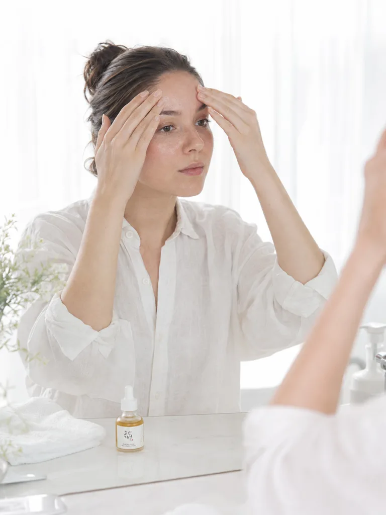 Woman with combination skin layering a lightweight propolis and niacinamide Korean essence under sunscreen