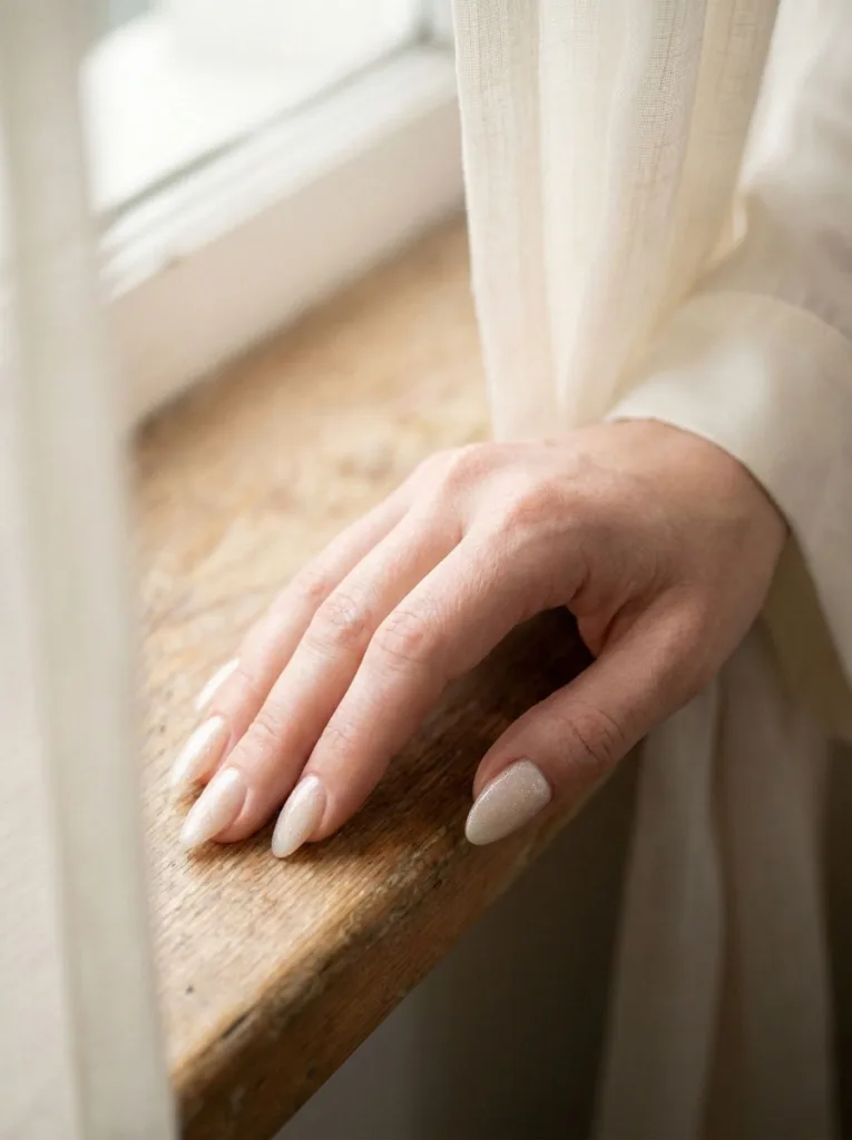 Ivory quartz shimmer wedding nails catching soft daylight near a window