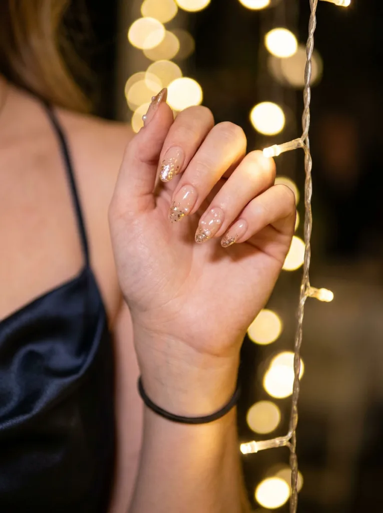 Pearl and glitter wedding nail design under warm reception string lights