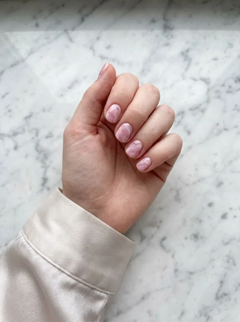 Pink and white marble swirl nail art on a matching marble countertop