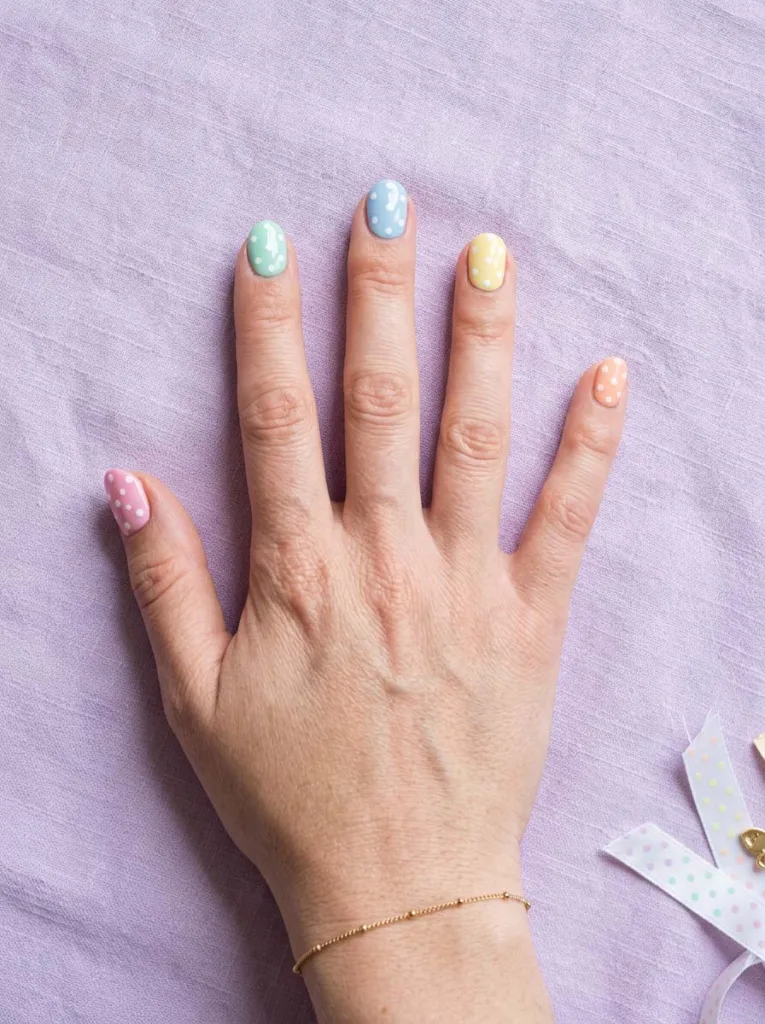 Polka dot pastel easter nails on hand resting on lavender fabric