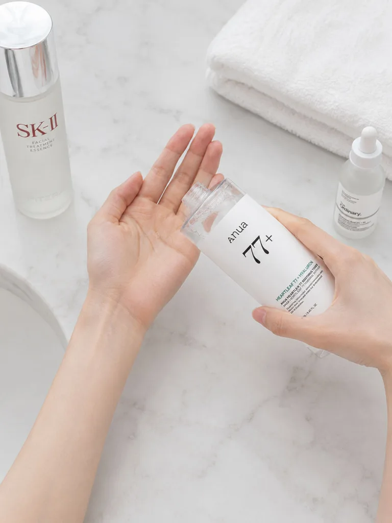 Close-up of hands applying Korean essence in the correct layering order between toner and serum