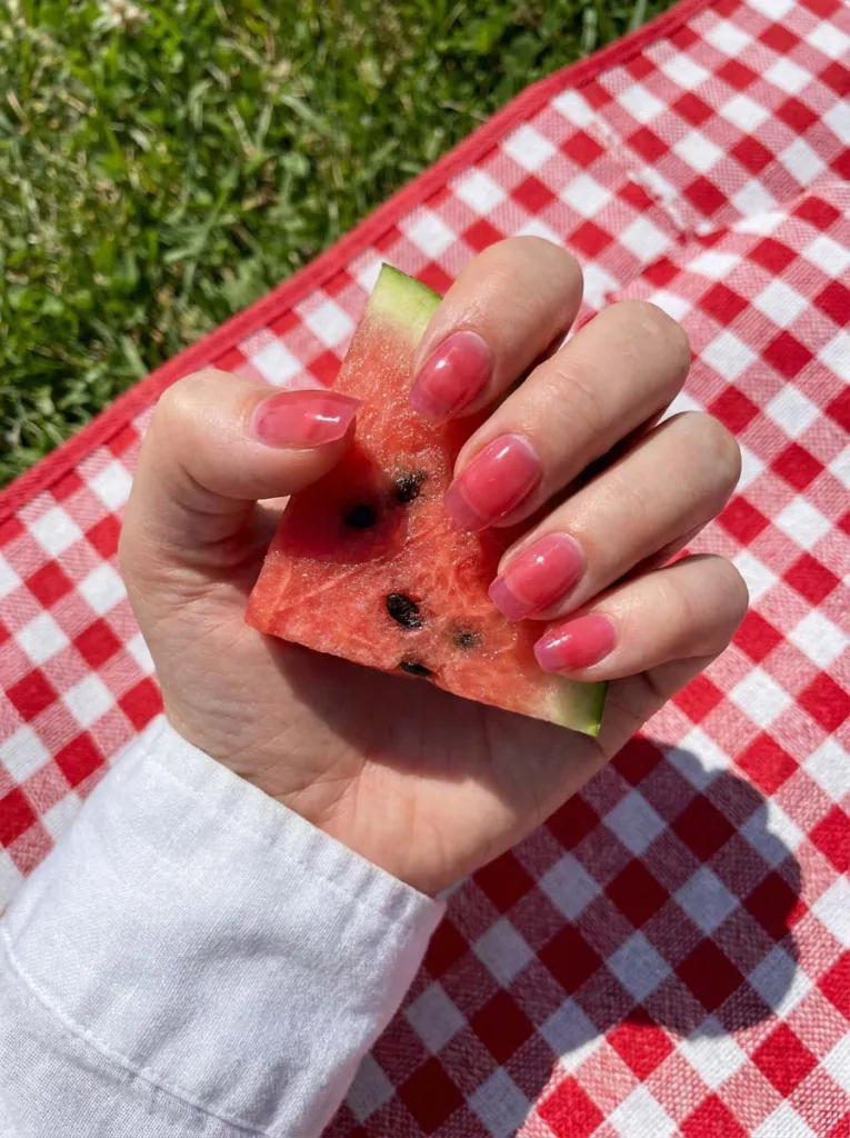 Translucent watermelon pink jelly nail polish holding a watermelon slice