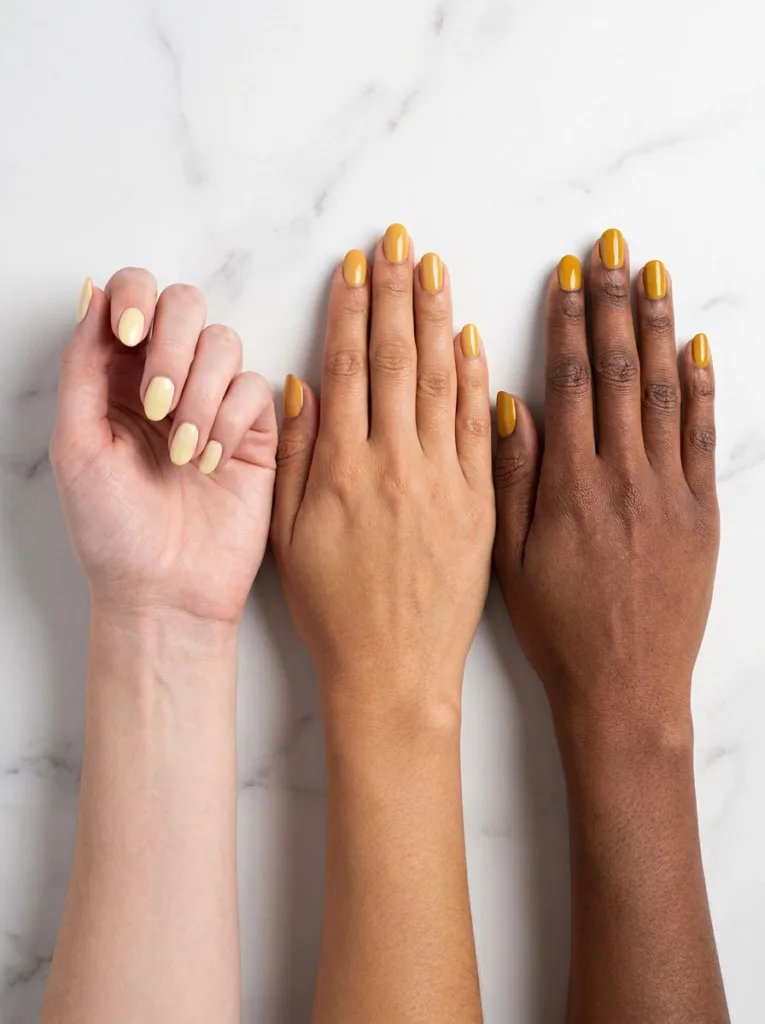 Three hands with cool, warm, and deep skin tones wearing matching yellow nail polish shades