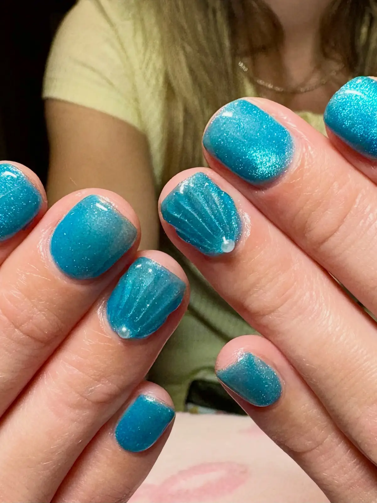 Short turquoise glitter nails with raised shell accents and small pearls