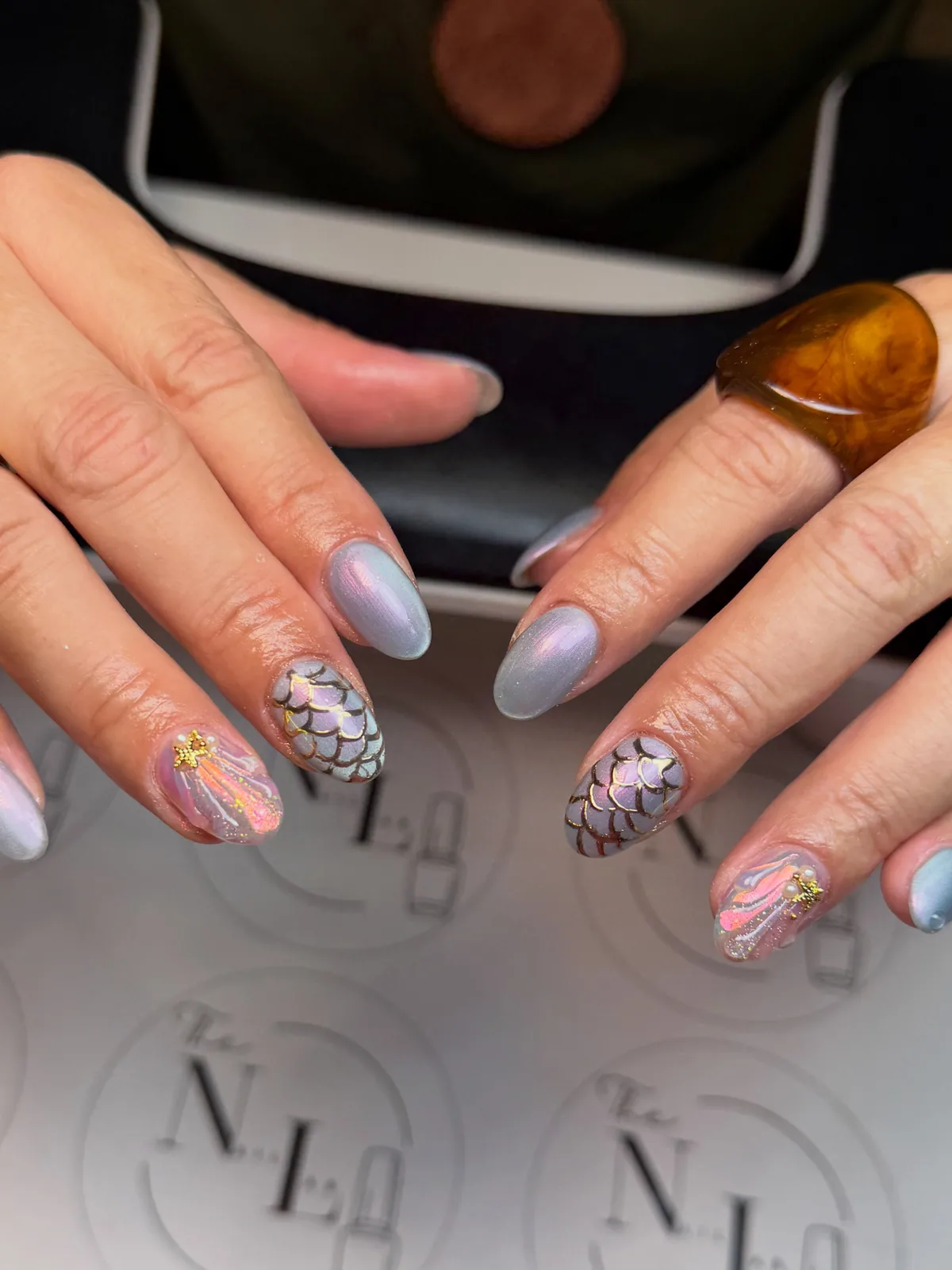 Pastel lilac-blue nails with iridescent scales, metallic outlines and small ocean accents