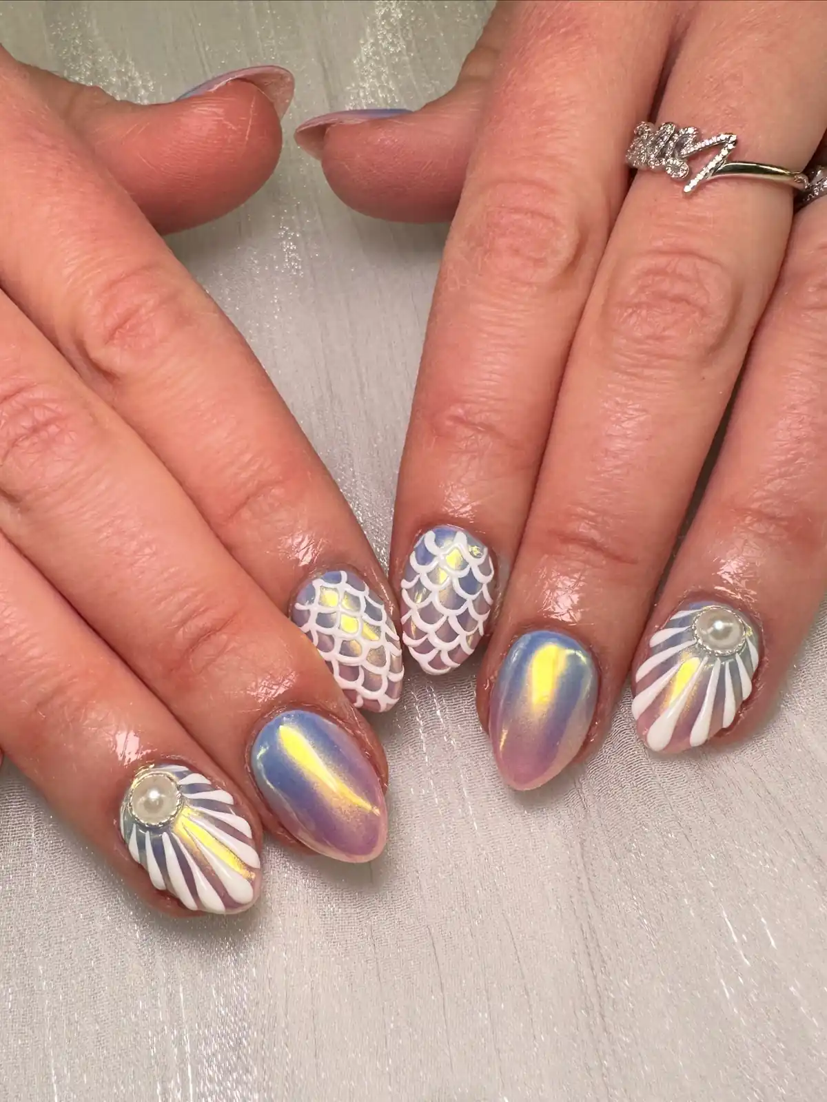Iridescent pink-purple nails with white scales, shell lines and pearl accents