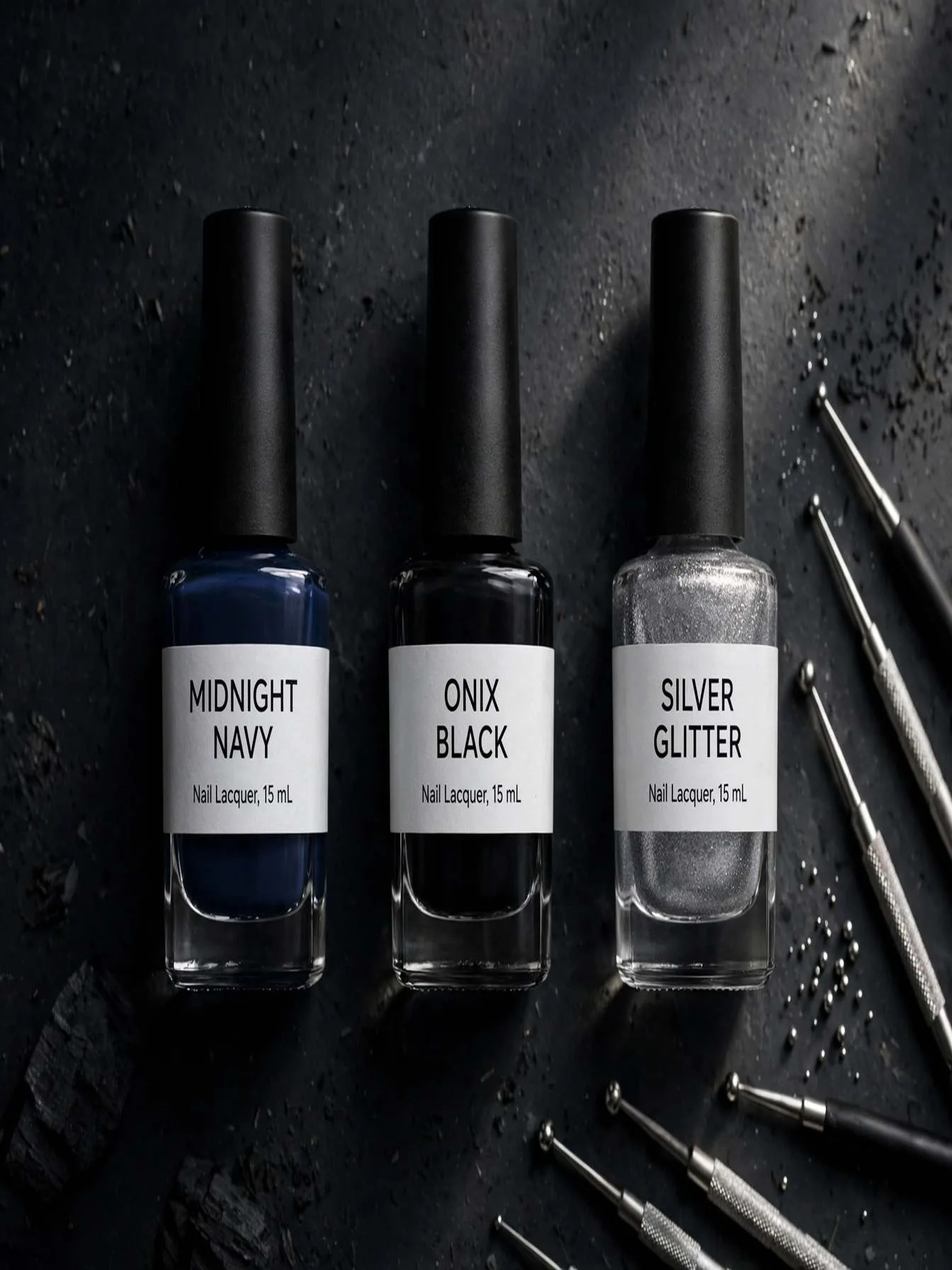 Flat lay of labeled nail polish bottles in midnight navy, onyx black and silver glitter with dotting tools on a dark surface